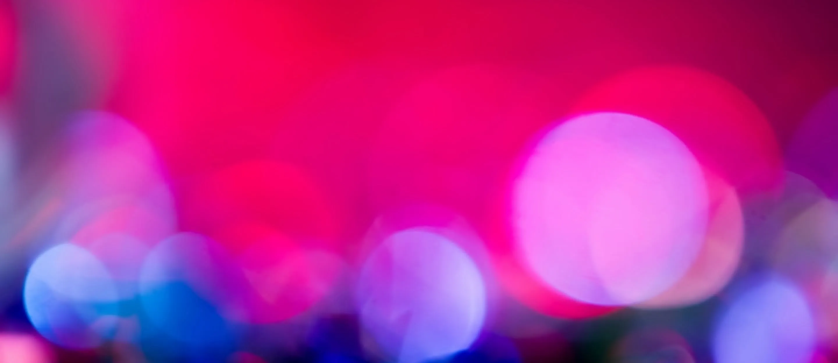 Blurry pink and blue background with out-of-focus circular light spots.