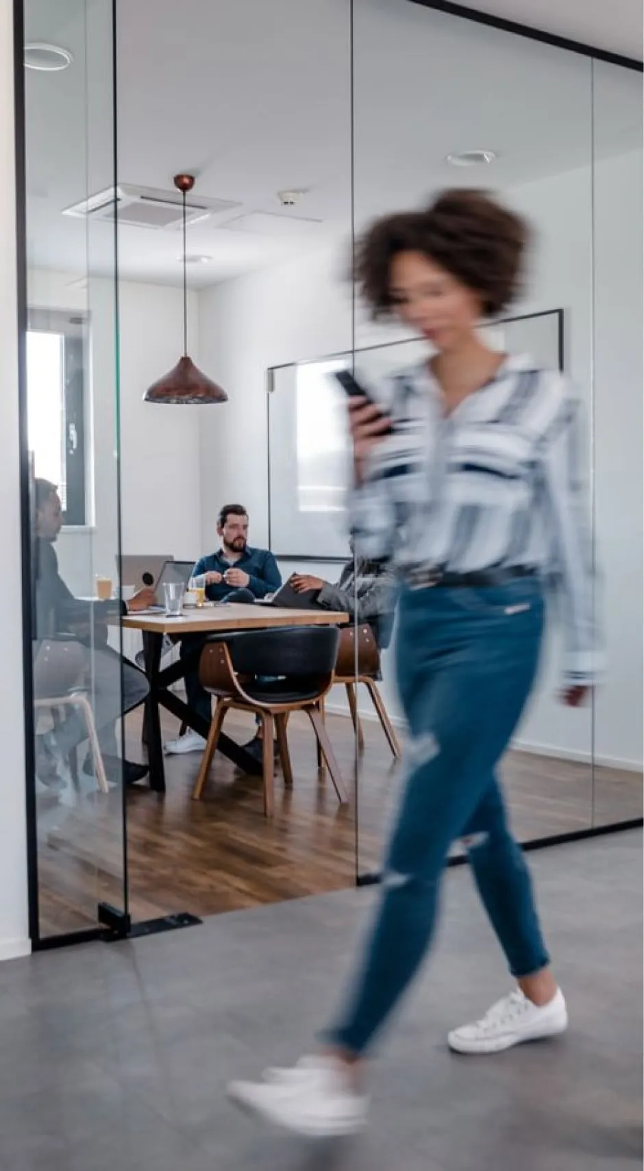 Woman walking down an office hallway, dressed casually.