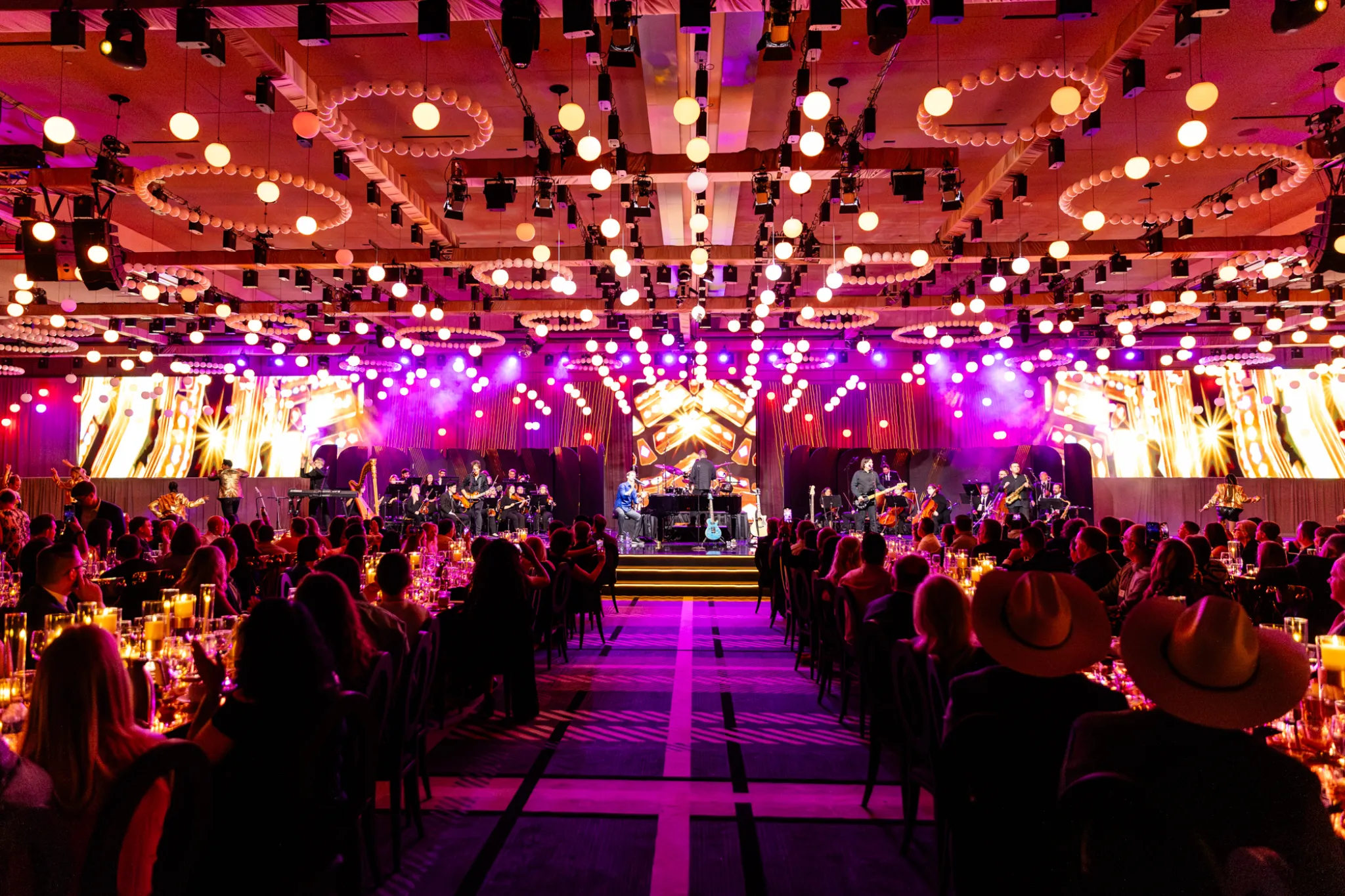 Ballroom set with dinner tables and a live band onstage at the incentive program reveal